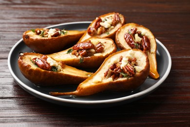 Photo of Delicious baked pears with nuts, blue cheese and honey on wooden table, closeup