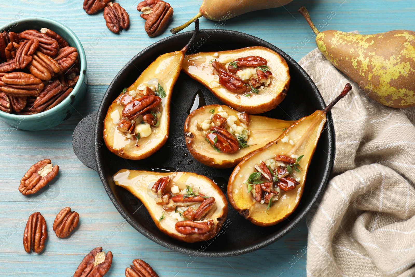 Photo of Delicious baked pears with nuts, blue cheese, thyme and honey on light blue wooden table, flat lay