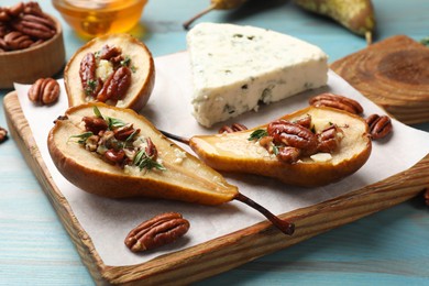 Photo of Delicious baked pears with nuts, blue cheese, thyme and honey on light blue wooden table, closeup