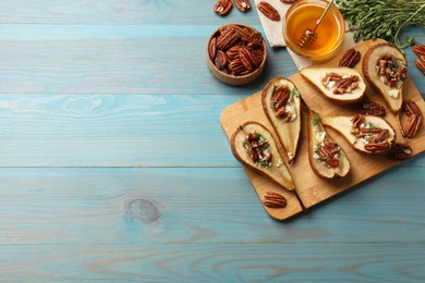 Photo of Delicious baked pears with nuts, blue cheese, thyme and honey on light blue wooden table, flat lay. Space for text