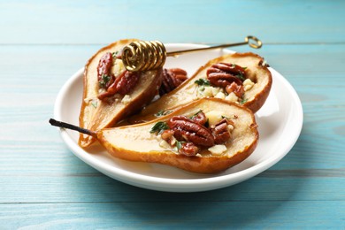 Photo of Delicious baked pears with nuts, blue cheese, thyme and honey on light blue wooden table