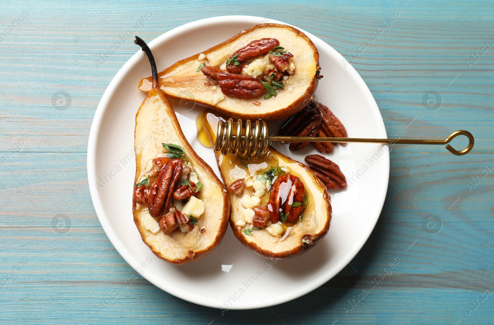 Photo of Delicious baked pears with nuts, blue cheese, thyme and honey on light blue wooden table, top view