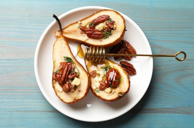 Delicious baked pears with nuts, blue cheese, thyme and honey on light blue wooden table, top view