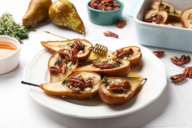 Photo of Delicious baked pears with nuts, blue cheese, thyme and honey on white tiled table, closeup