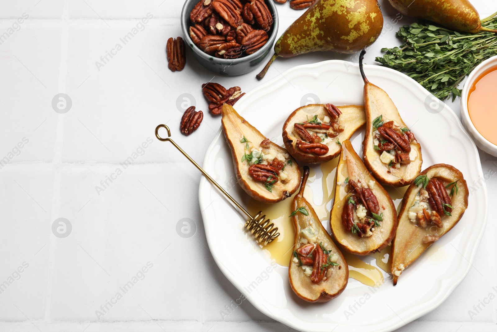 Photo of Delicious baked pears with nuts, blue cheese, thyme and honey on white tiled table, flat lay. Space for text