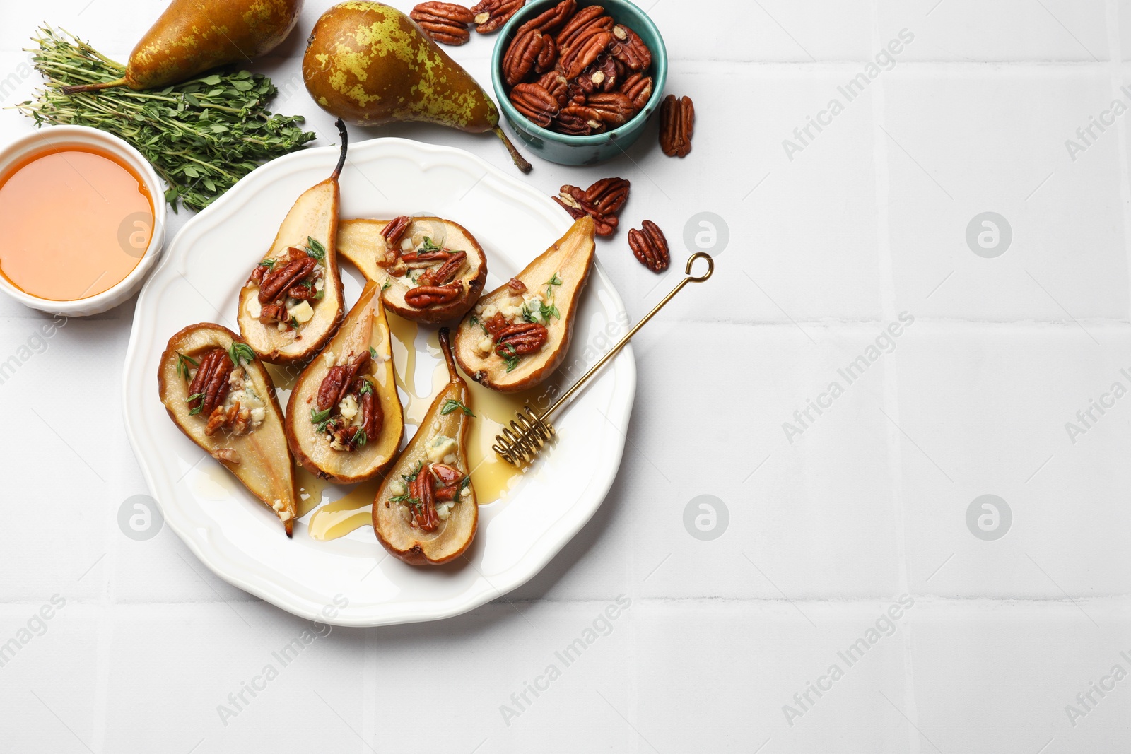 Photo of Delicious baked pears with nuts, blue cheese, thyme and honey on white tiled table, flat lay. Space for text