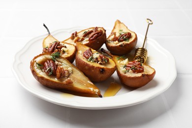 Delicious baked pears with nuts, blue cheese, thyme and honey on white tiled table, closeup