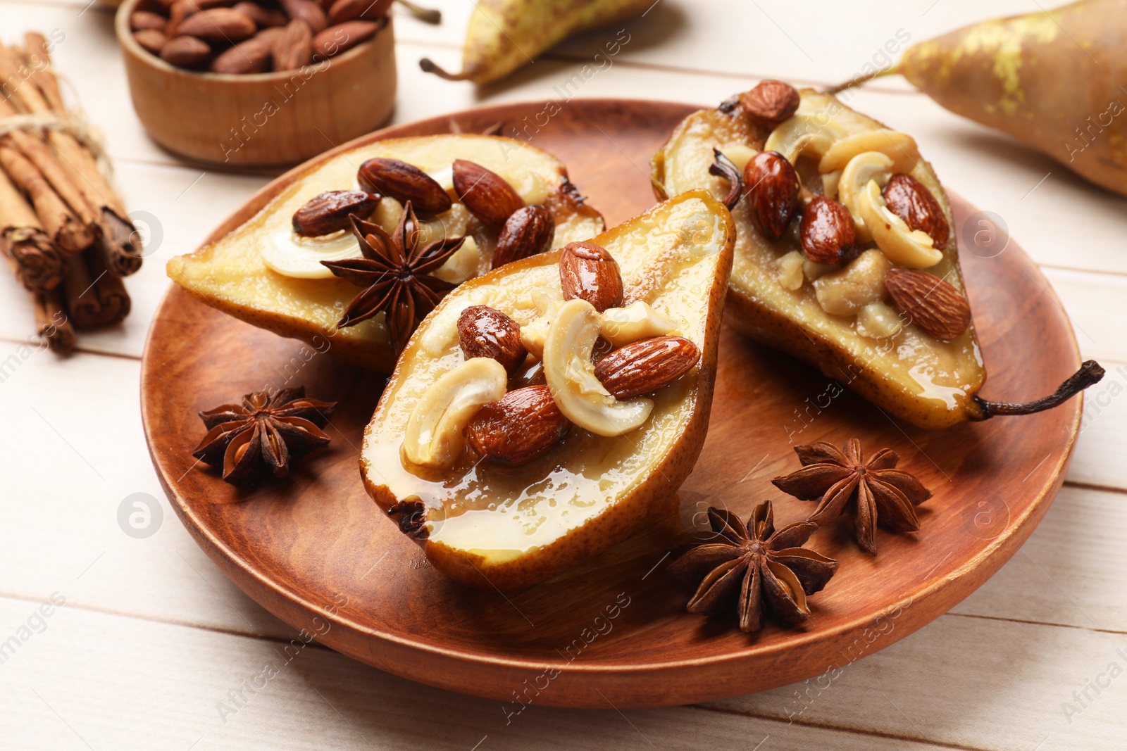 Photo of Delicious baked pears with nuts and anise stars on light wooden table, closeup