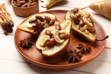 Delicious baked pears with nuts and anise stars on light wooden table, closeup