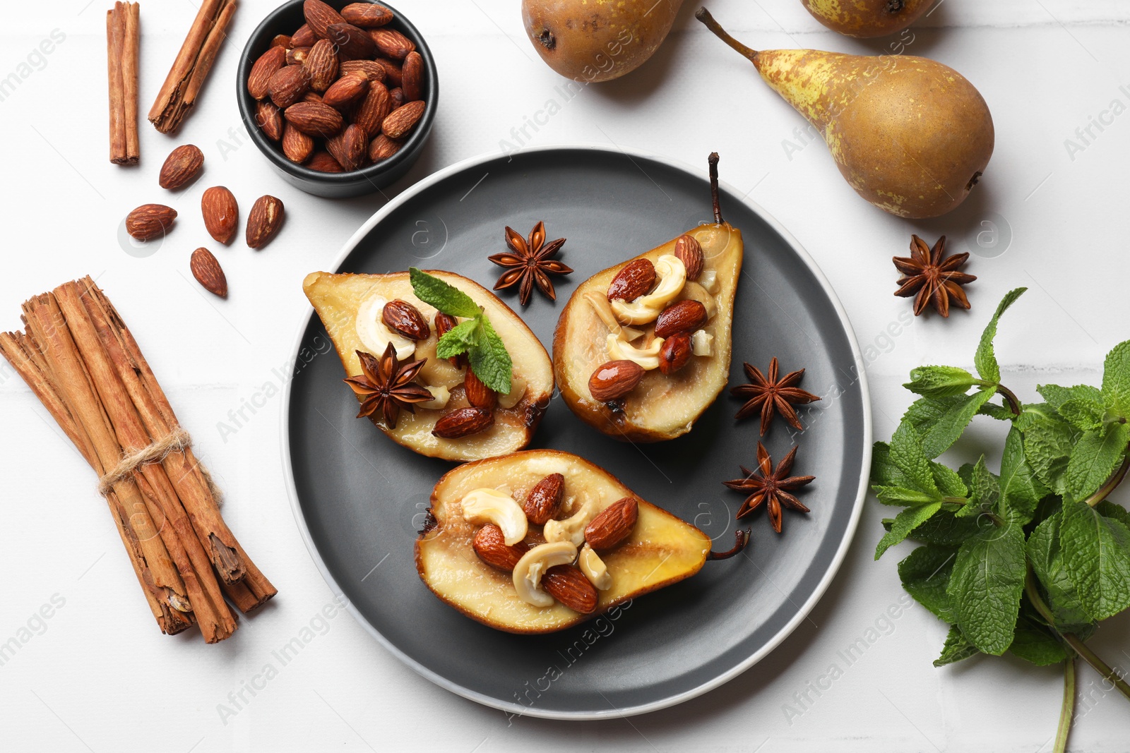 Photo of Delicious baked pears with nuts, mint and anise stars on white table, flat lay