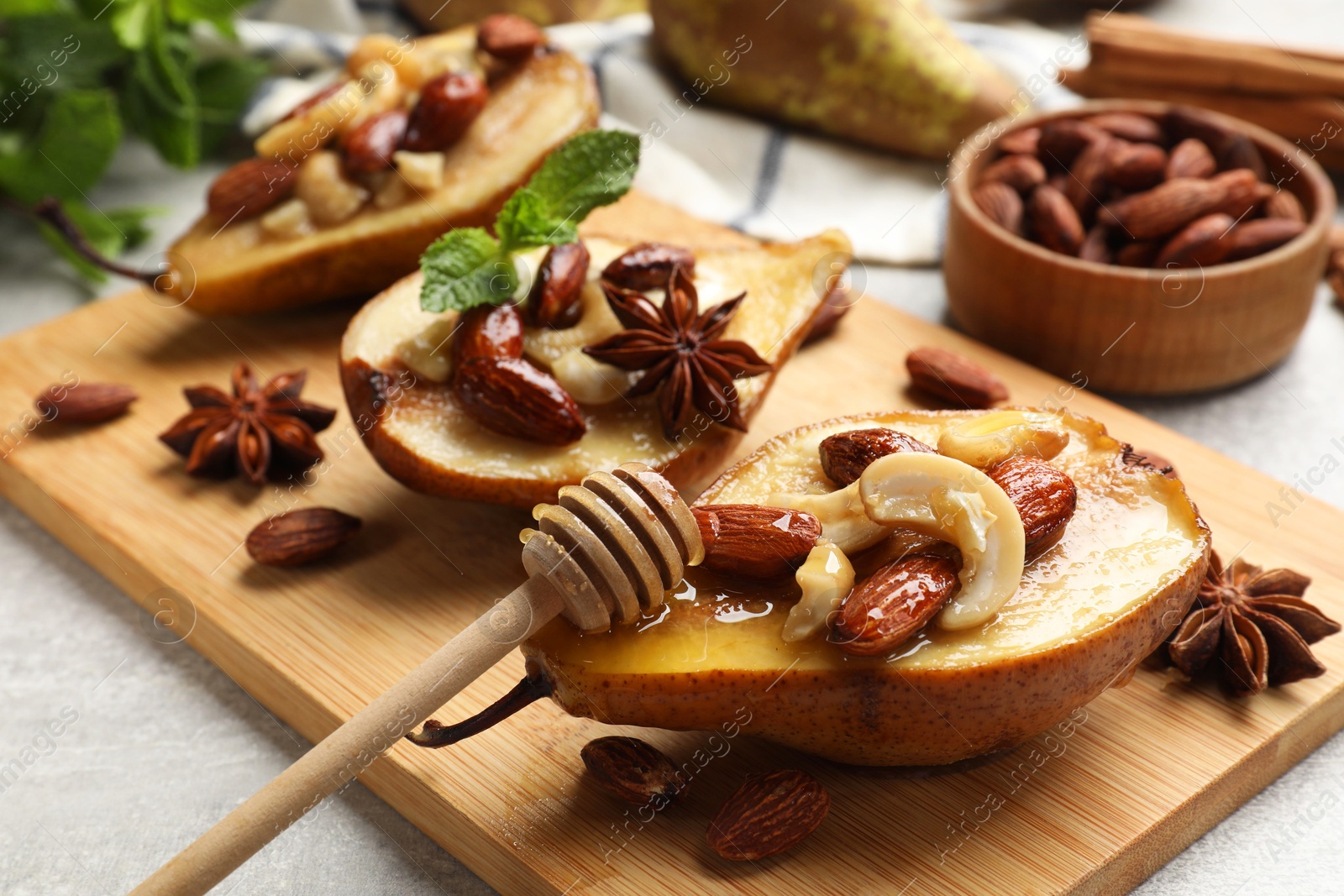 Photo of Delicious baked pears with nuts, honey, dipper and anise stars on light textured table, closeup