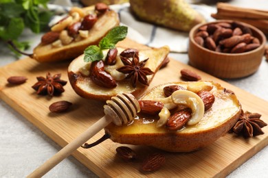 Photo of Delicious baked pears with nuts, honey, dipper and anise stars on light textured table, closeup