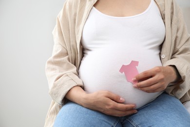 Pregnant woman with pink paper T-shirt on light background, closeup