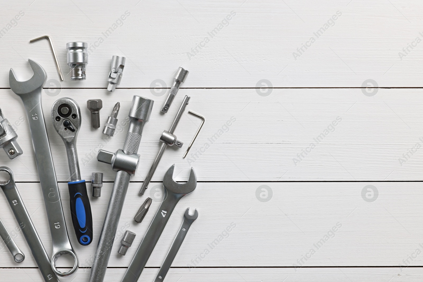 Photo of Auto mechanic's tools on white wooden table, flat lay. Space for text