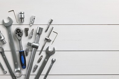 Photo of Auto mechanic's tools on white wooden table, flat lay. Space for text