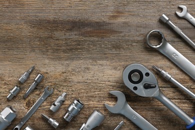 Photo of Different auto mechanic's tools on wooden table, flat lay. Space for text