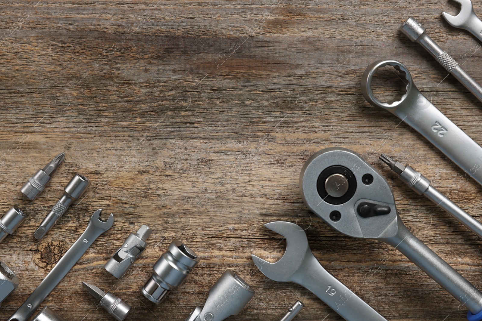 Photo of Different auto mechanic's tools on wooden table, flat lay. Space for text