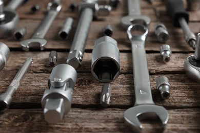 Photo of Different auto mechanic's tools on wooden table, closeup