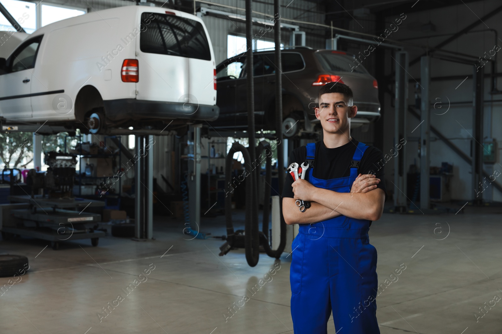 Photo of Young auto mechanic with wrenches at automobile repair shop