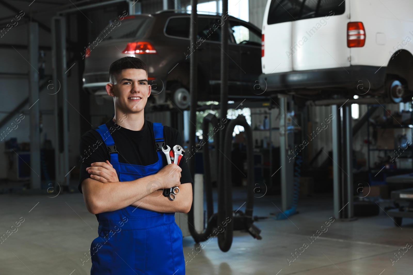 Photo of Young auto mechanic with wrenches at automobile repair shop