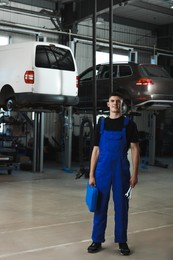 Young auto mechanic with different tools at automobile repair shop