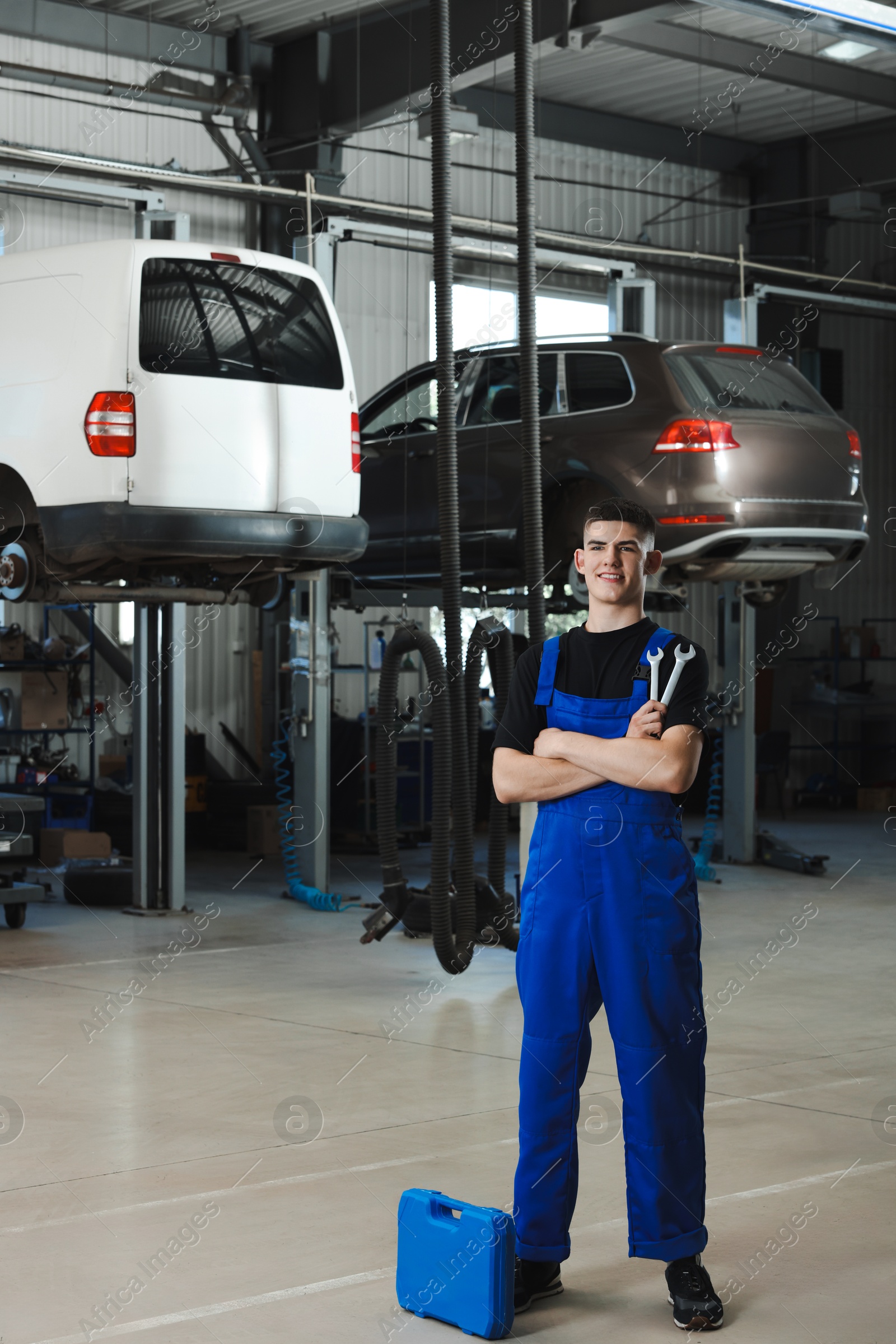 Photo of Young auto mechanic with different tools at automobile repair shop