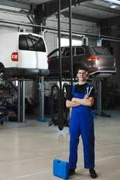 Young auto mechanic with different tools at automobile repair shop