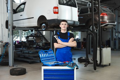 Photo of Young auto mechanic with different tools at automobile repair shop