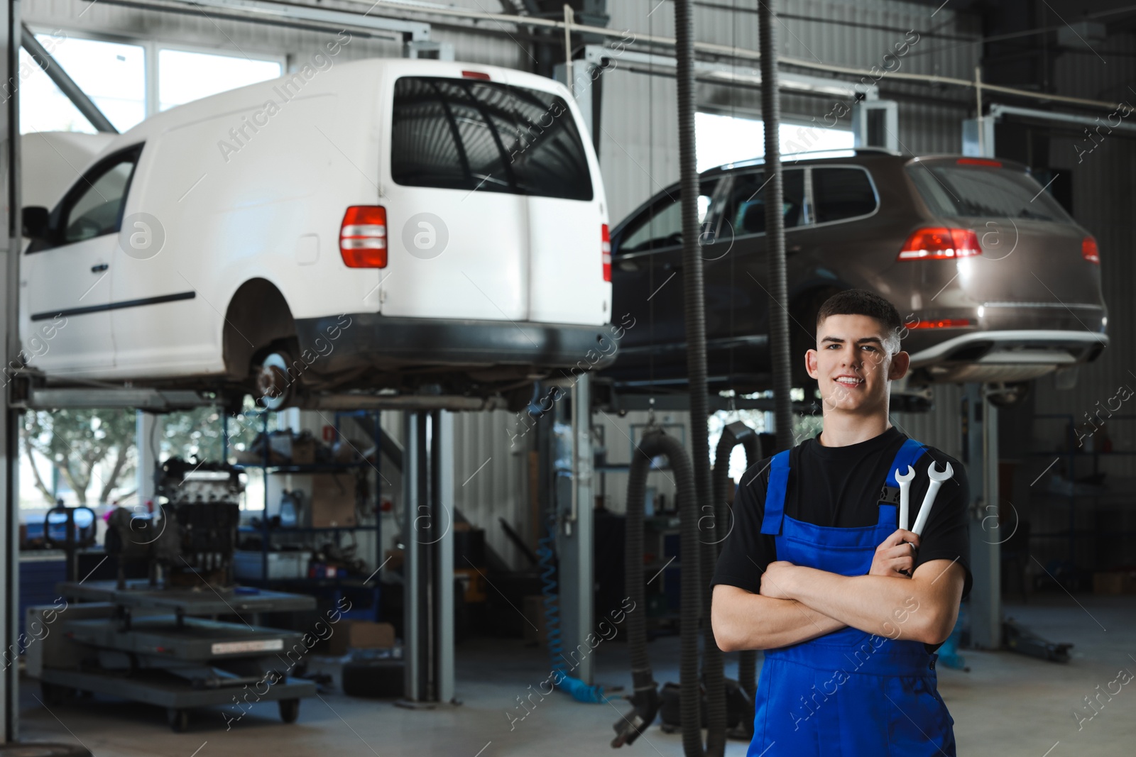 Photo of Young auto mechanic with wrenches at automobile repair shop