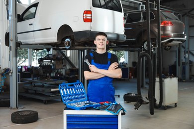 Young auto mechanic with different tools at automobile repair shop