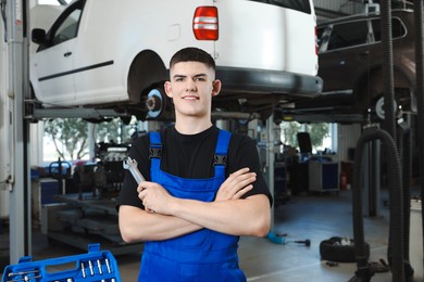 Photo of Young auto mechanic with wrenches at automobile repair shop