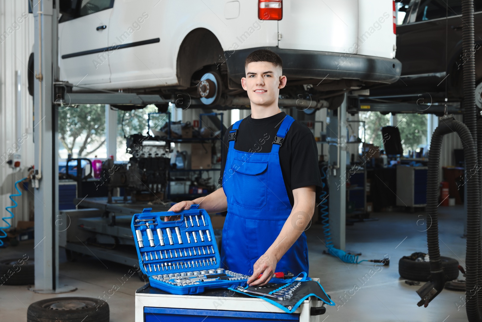 Photo of Young auto mechanic with different tools at automobile repair shop