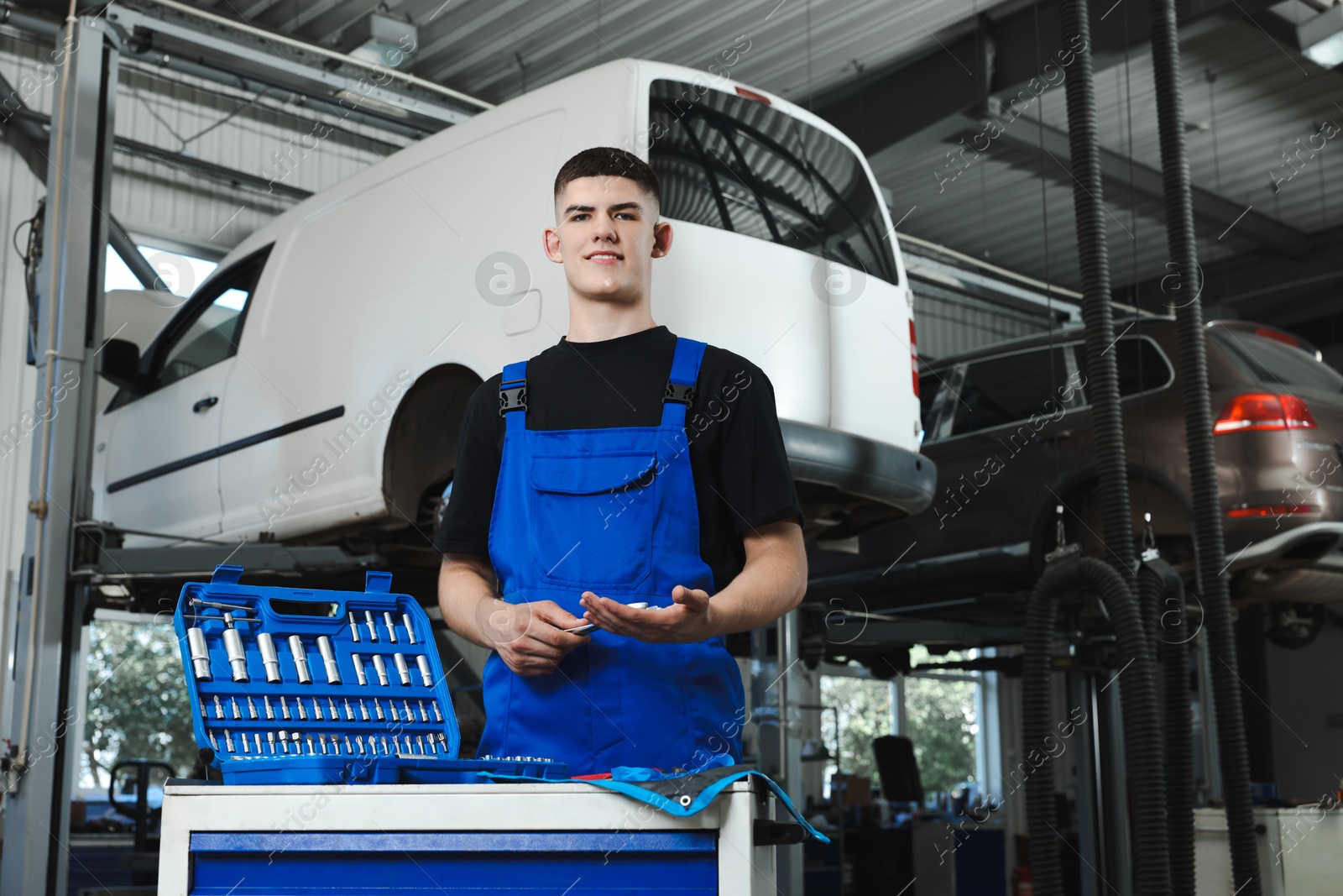 Photo of Young auto mechanic with different tools at automobile repair shop