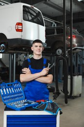 Young auto mechanic with different tools at automobile repair shop