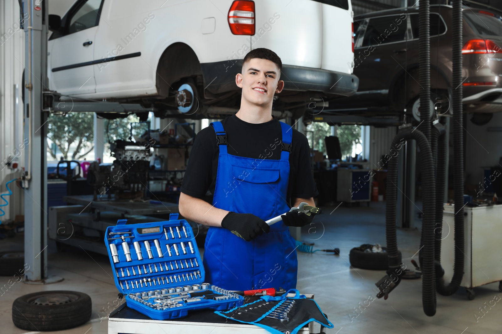 Photo of Young auto mechanic with different tools at automobile repair shop