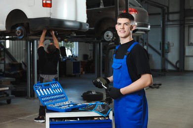 Young auto mechanic with different tools at automobile repair shop