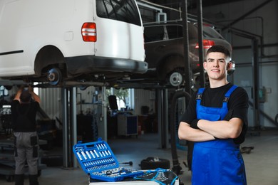 Young auto mechanic with different tools at automobile repair shop