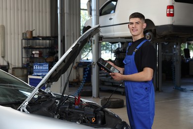 Photo of Young auto mechanic fixing car at automobile repair shop