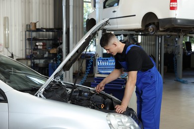 Photo of Young auto mechanic fixing car at automobile repair shop