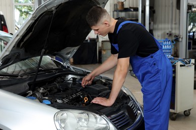 Young auto mechanic fixing car at automobile repair shop