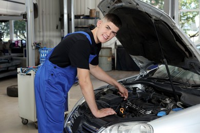 Young auto mechanic fixing car at automobile repair shop