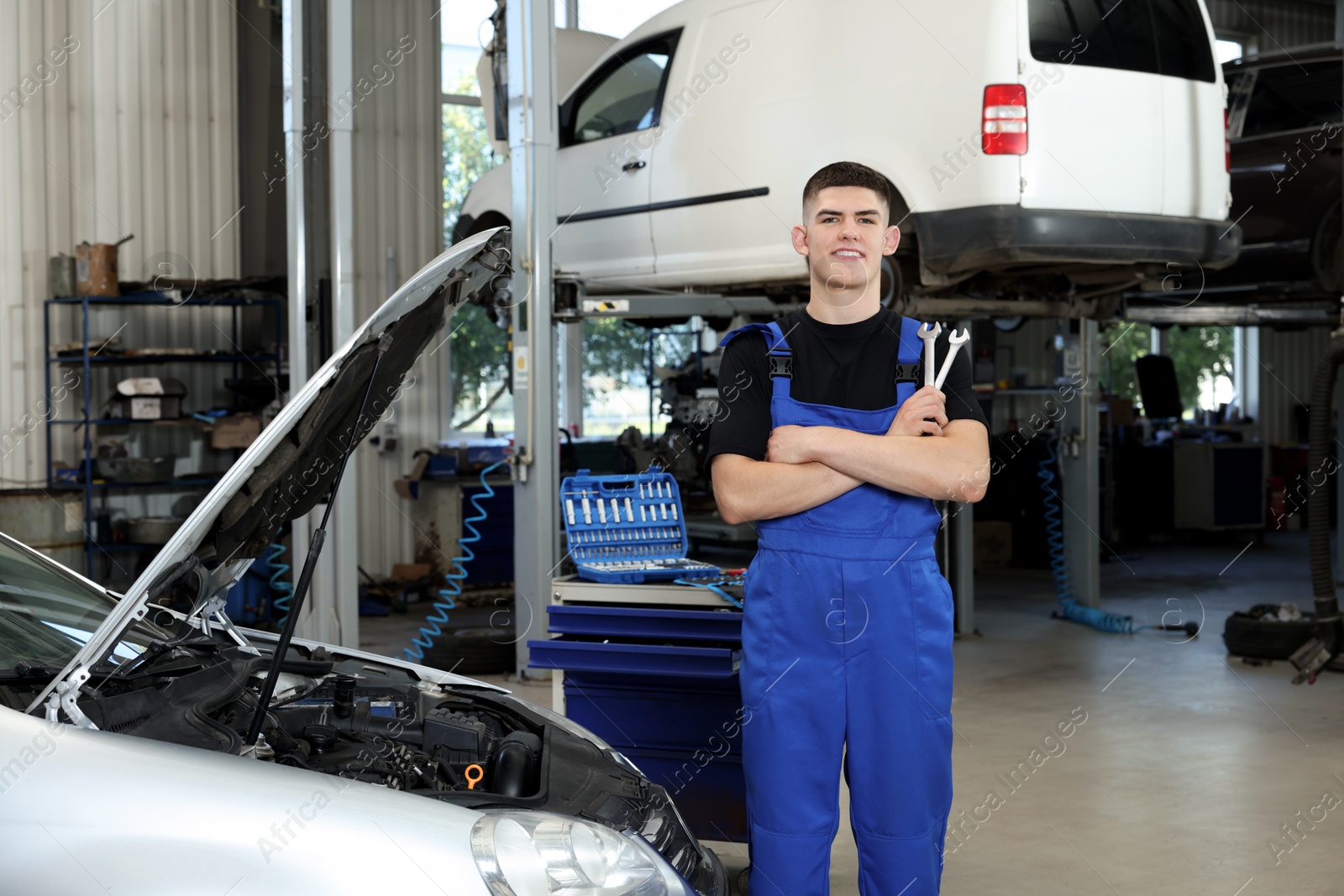 Photo of Young auto mechanic near broken car at automobile repair shop