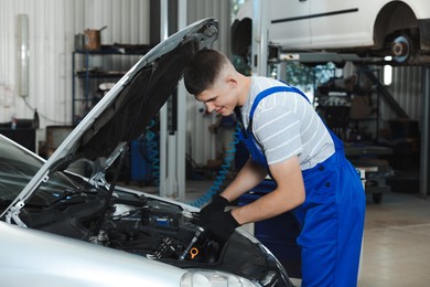 Photo of Young auto mechanic fixing car at automobile repair shop