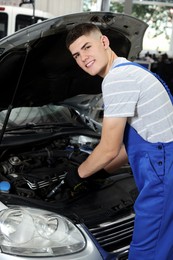 Photo of Young auto mechanic fixing car at automobile repair shop