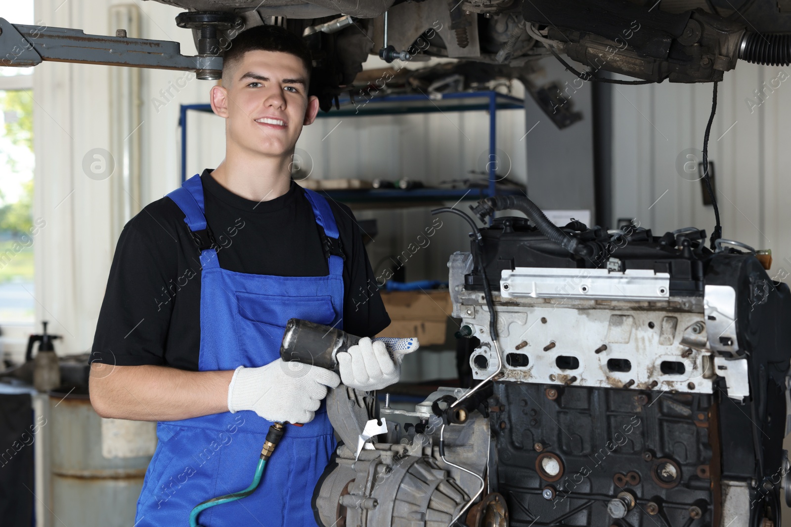 Photo of Young auto mechanic fixing motor at automobile repair shop. Car diagnostic