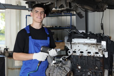 Photo of Young auto mechanic fixing motor at automobile repair shop. Car diagnostic