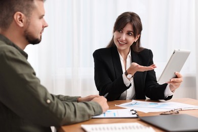 Photo of Smiling consultant working with client at table in office. Business meeting