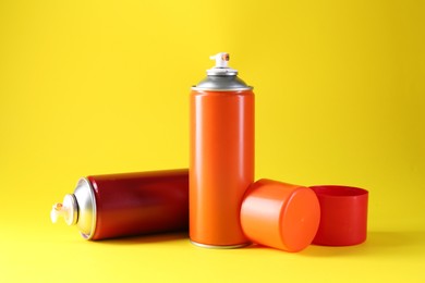 Photo of Two spray paint cans on yellow background