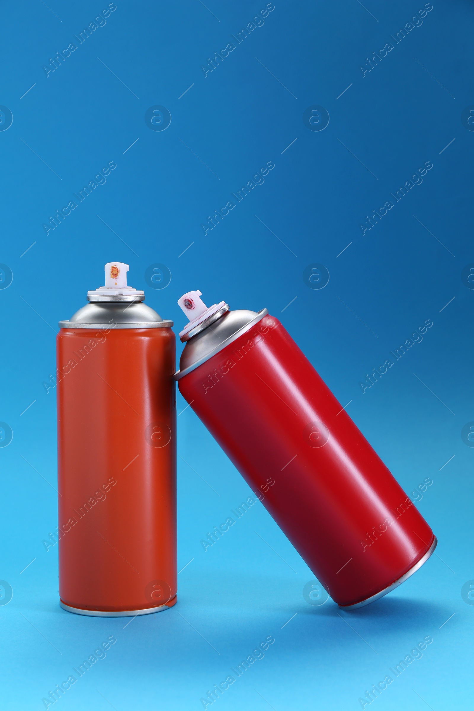 Photo of Two spray paint cans on light blue background