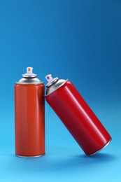 Photo of Two spray paint cans on light blue background